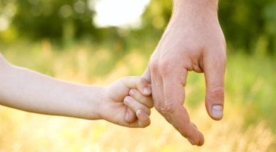 trust family hands of child son and father on wheat field nature