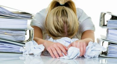 a young woman desperately in office between many file folders an