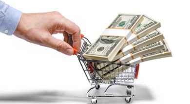 businessman’s hand & steel grocery cart full of money stacks – i